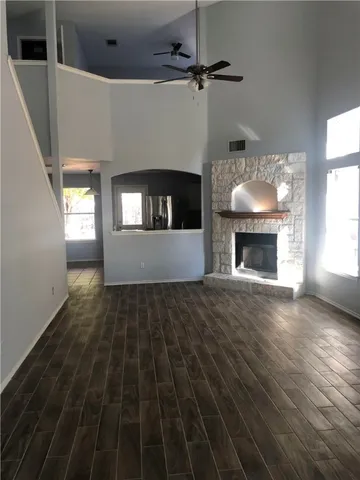 a view of an empty room with wooden floor fireplace and a window