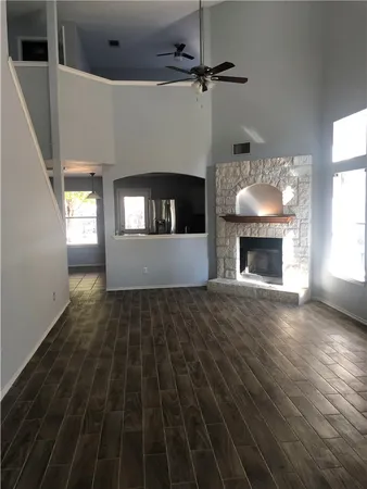 a view of an empty room with wooden floor fireplace and a window