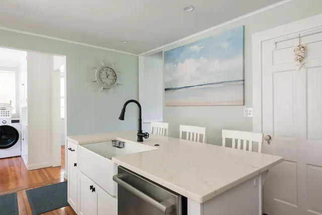 a kitchen with stainless steel appliances a white refrigerator a sink a stove and white cabinets with wooden floor