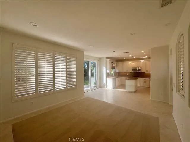a view of an empty room with kitchen and a window