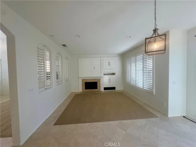 a view of a livingroom with a fireplace a chandelier and windows