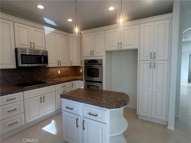a kitchen with kitchen island granite countertop stainless steel appliances a stove a microwave and sink