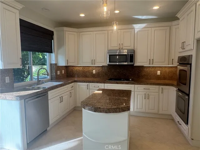 a kitchen with stainless steel appliances granite countertop a stove a sink and a microwave