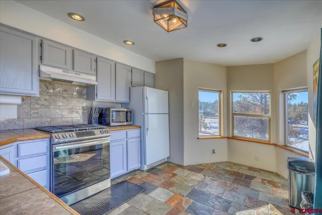 a kitchen with stainless steel appliances granite countertop a refrigerator and a stove top oven