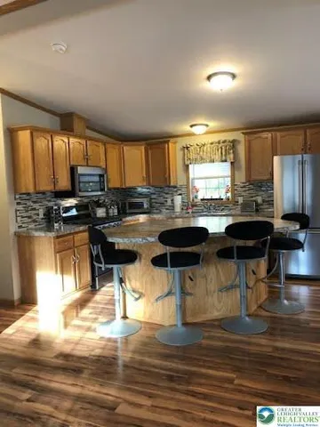 a kitchen with stainless steel appliances granite countertop a stove top oven a refrigerator a stove and white cabinets with wooden floor