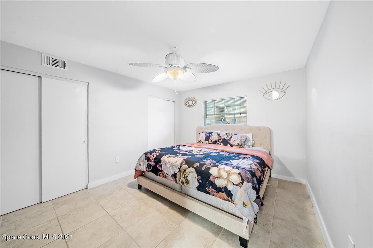 151 Ulster Lane Melbourne, FL 32935 - Photo 10 of 14 a bedroom with a bed and a chandelier