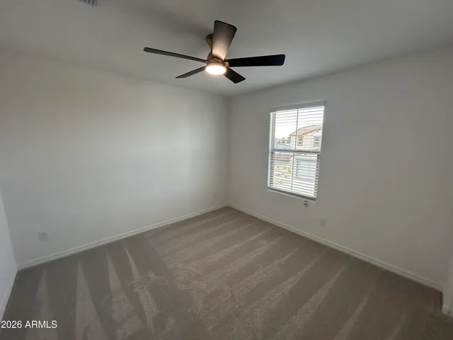 an empty room with a ceiling fan and window