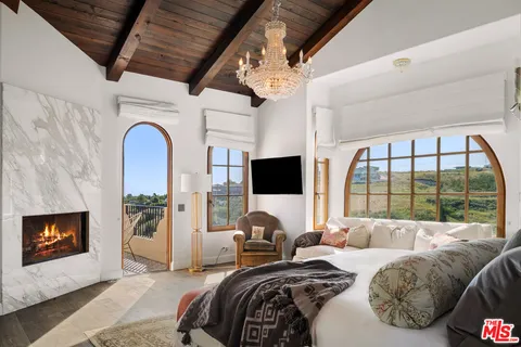 a bedroom with furniture a flat screen tv and a fireplace