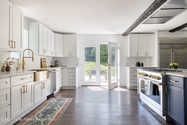 a kitchen with stainless steel appliances granite countertop a stove top oven a sink dishwasher and white cabinets with wooden floor