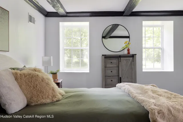 a bedroom with a bed a mirror and a window