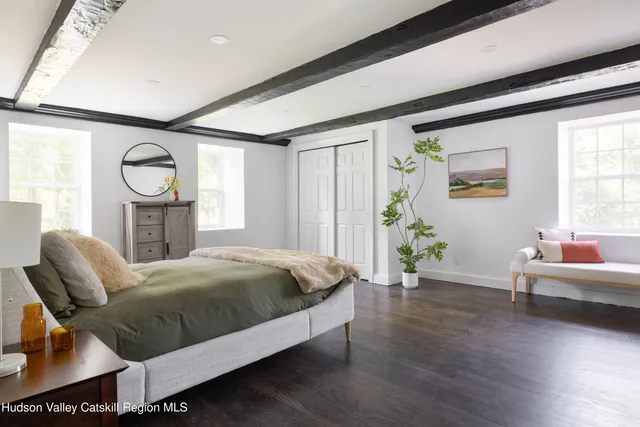 a spacious bedroom with a bed and wooden floor