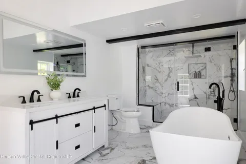 a bathroom with a bathtub shower sink mirror and toilet