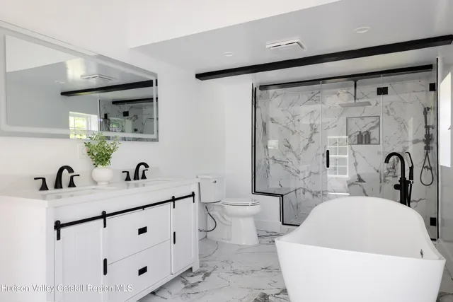 a bathroom with a bathtub shower sink mirror and toilet