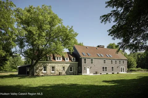 a view of a white house in front of a big yard with large trees