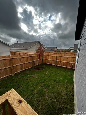 a view of a backyard with brick wall and wooden fence