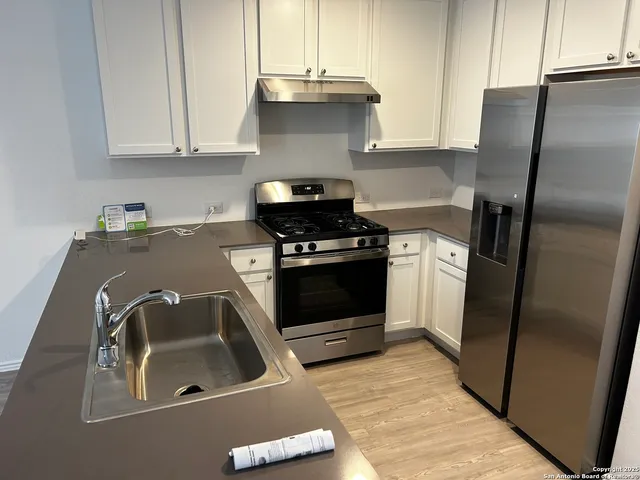 a kitchen with a sink a refrigerator and cabinets
