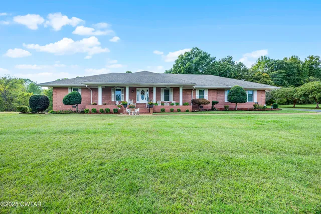 a view of a house with a big yard and large trees