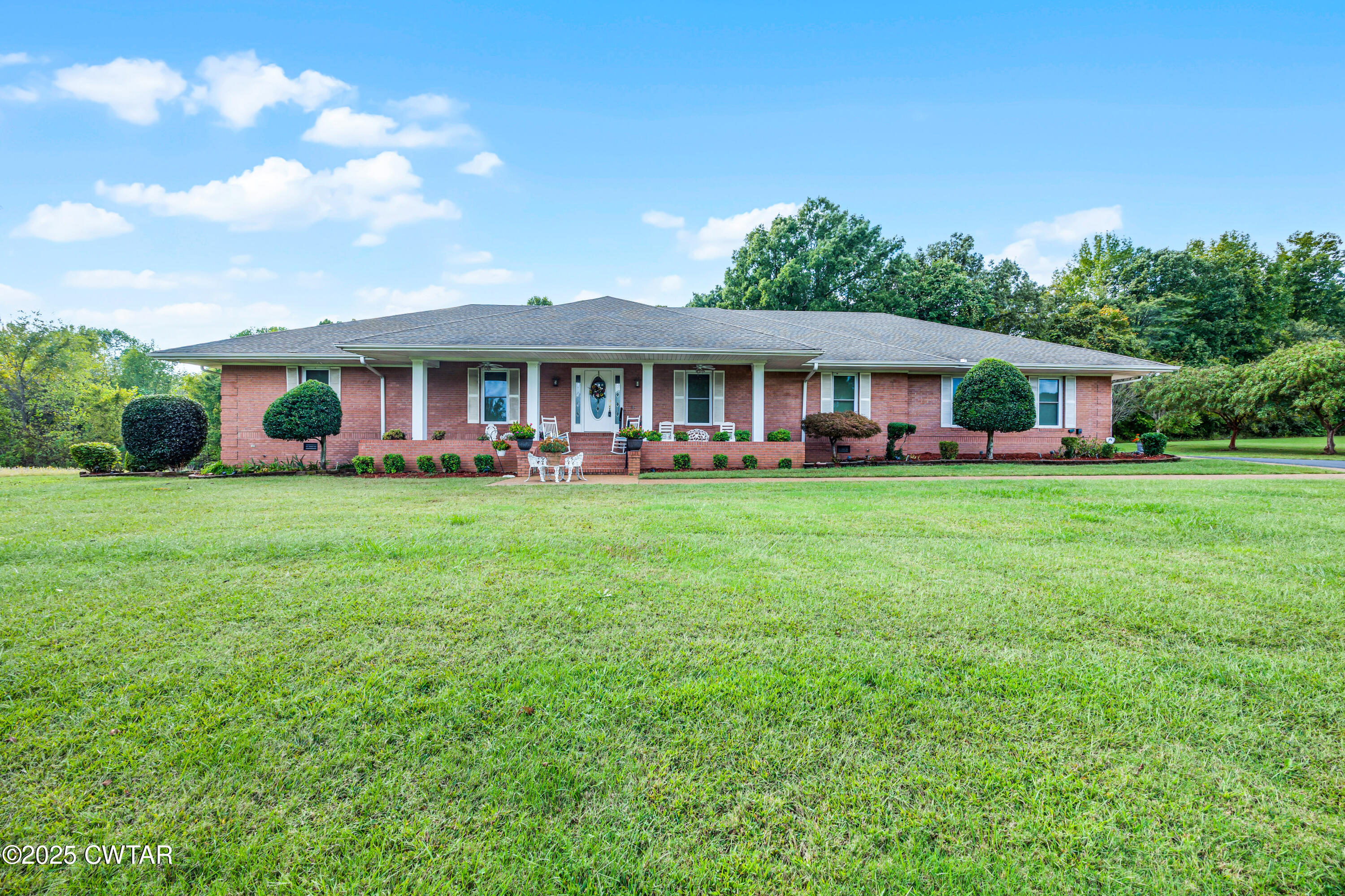 a view of a house with a big yard and large trees