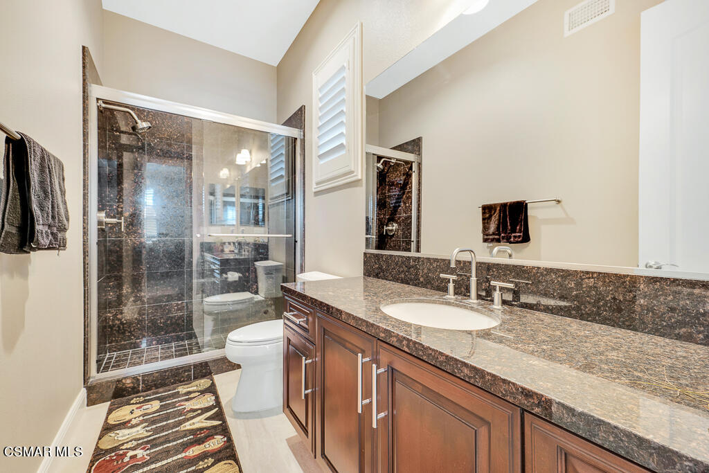 7379 Nicklaus Road Moorpark, CA 93021 - Photo 31 of 85 a bathroom with a granite countertop sink a mirror and a shower