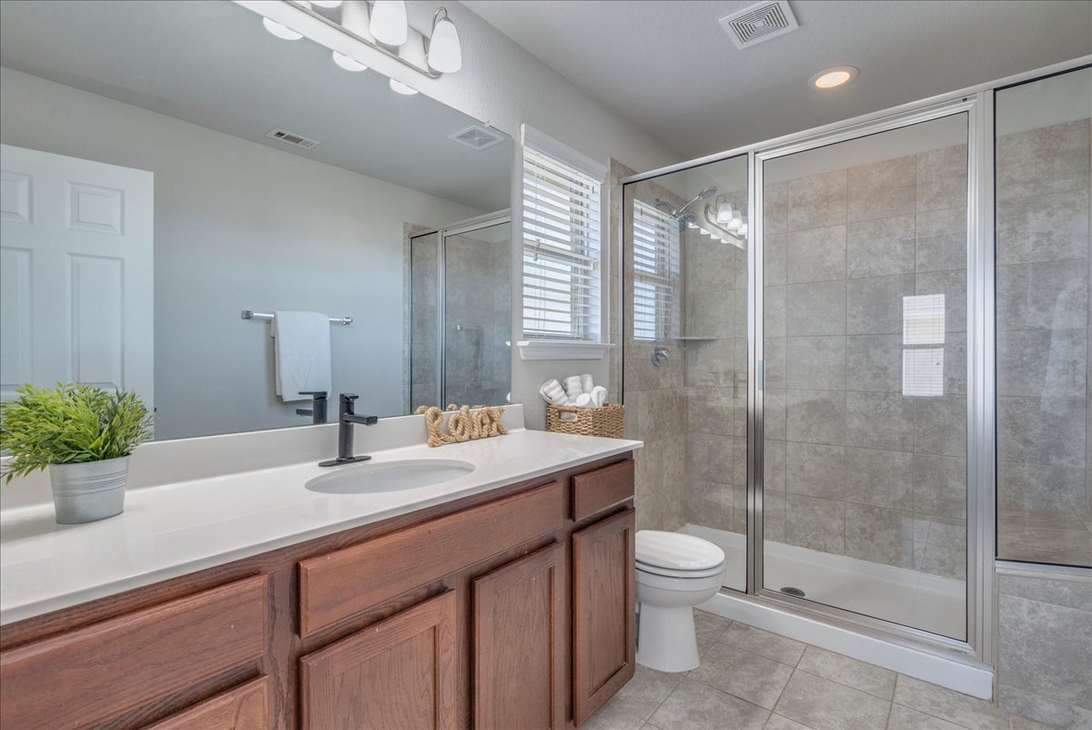 312 Triumph Road Buda, TX 78610 - Photo 25 of 36 a bathroom with a shower sink vanity mirror and toilet