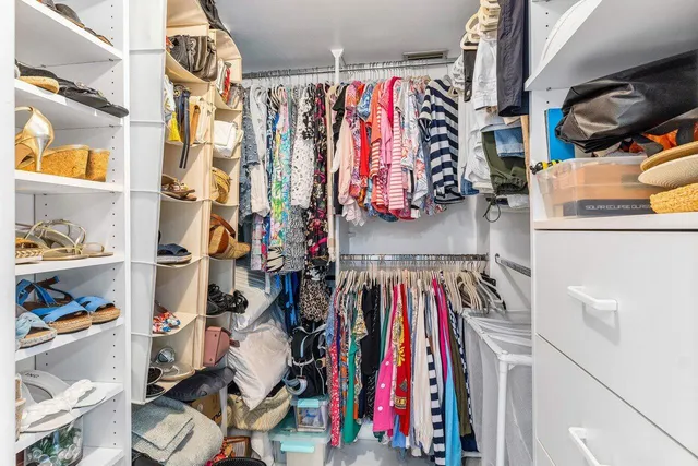 a view of walk in closet with clothes and shoes