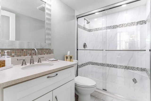 a bathroom with a granite countertop sink mirror vanity and toilet