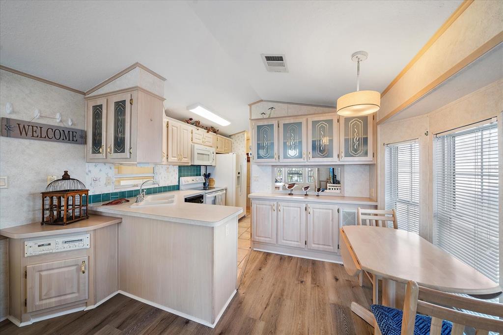 14 Basin Street Palmetto, FL 34221 - Photo 12 of 27 a kitchen with a sink dishwasher a stove a microwave oven with white cabinets and wooden floor