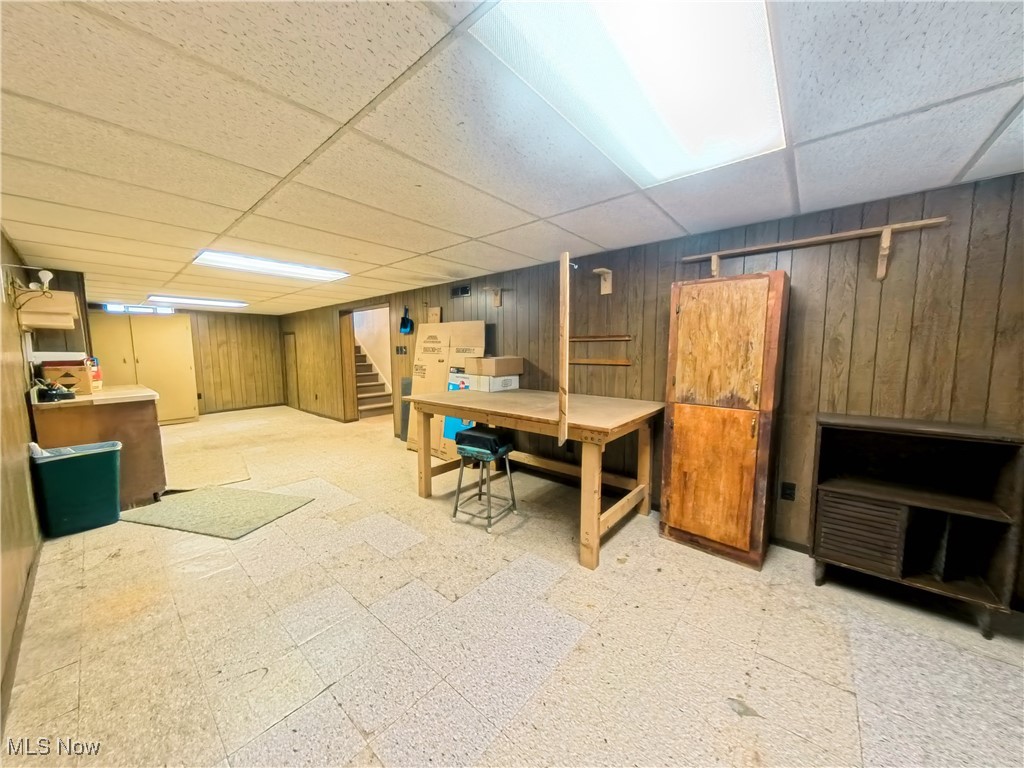 1668 Harwich Road Cleveland, OH 44124 - Photo 15 of 19 Finished basement featuring light flooring, a drop ceiling, wooden walls, and stairs