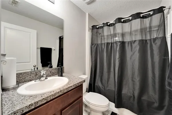 a bathroom with a granite countertop sink toilet and shower