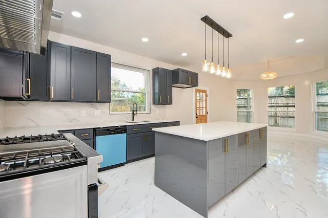 a kitchen with kitchen island a sink stove top oven and cabinets