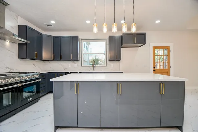 a kitchen with kitchen island granite countertop a sink cabinets and stainless steel appliances