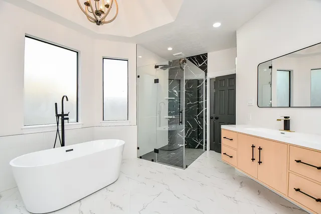 a spacious bathroom with a tub sink shower and mirror