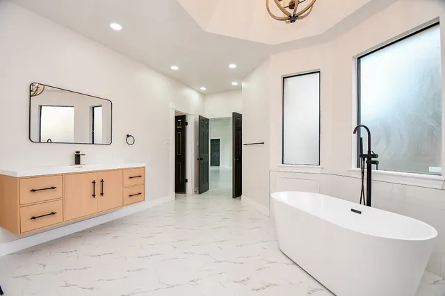 a large bathroom with a tub sink and mirror