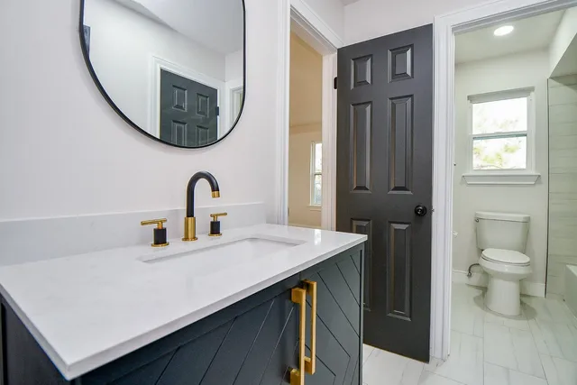 a bathroom with a sink a toilet and a mirror