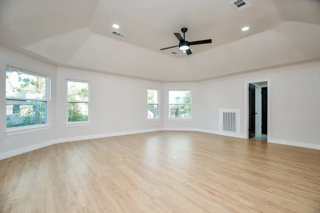 a view of an empty room with a window and wooden floor