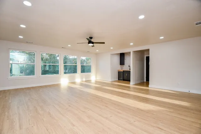 a view of an empty room with wooden floor and a window