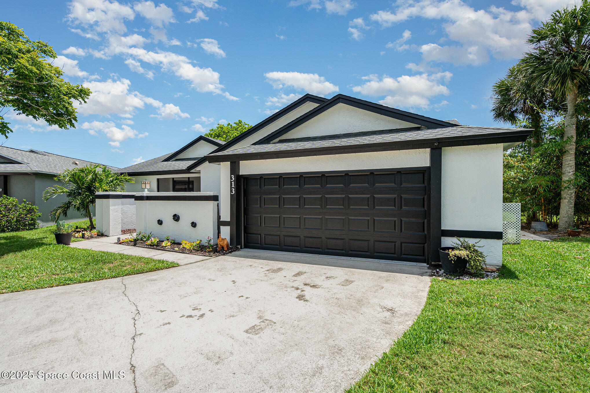 313 Pine Ridge Lane Melbourne, FL 32940 - Photo 2 of 28 a front view of a house with a yard and garage