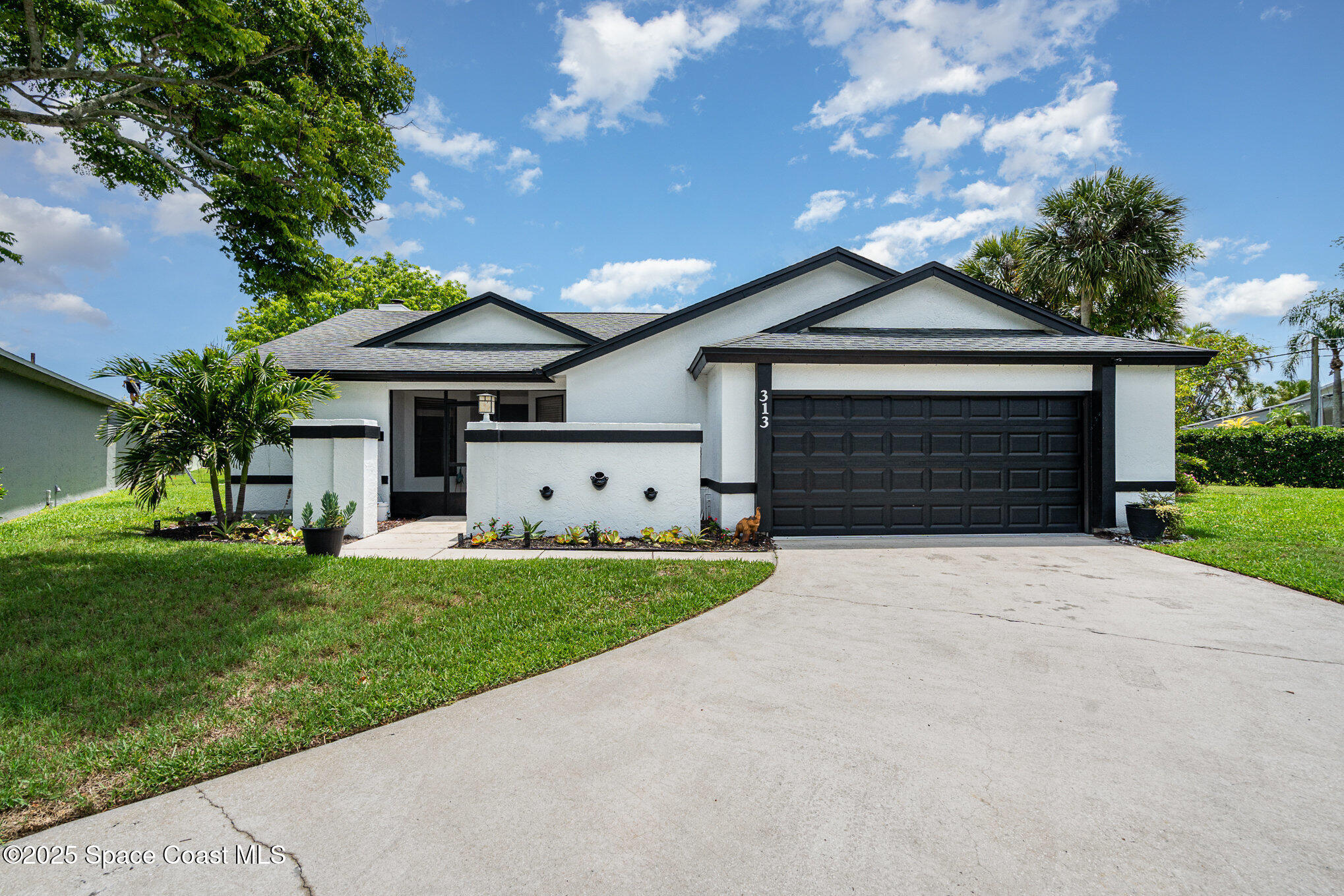 313 Pine Ridge Lane Melbourne, FL 32940 - Photo 4 of 28 a front view of a house with a yard and garage