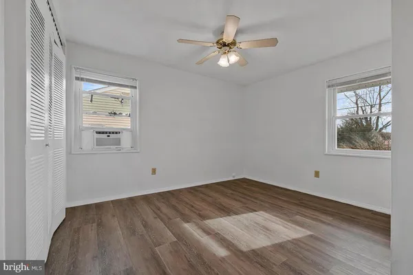 a view of an empty room with window and wooden floor