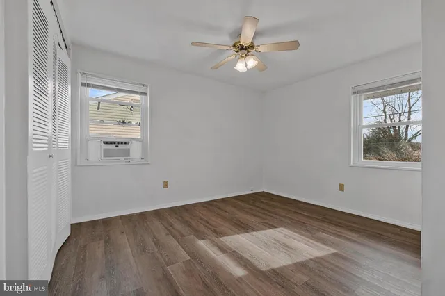 a view of an empty room with window and wooden floor