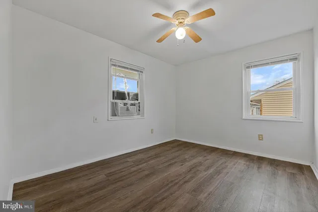 a view of empty room with wooden floor and fan
