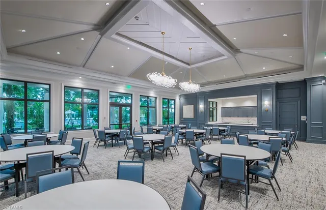 a room with lots of tables a large window and chairs