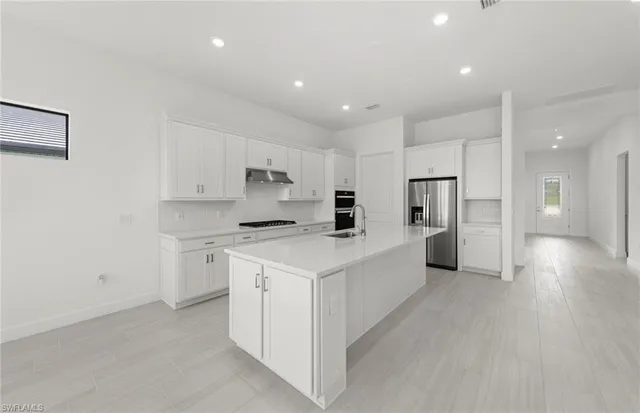 a large kitchen with stainless steel appliances a white stove top oven and white cabinets