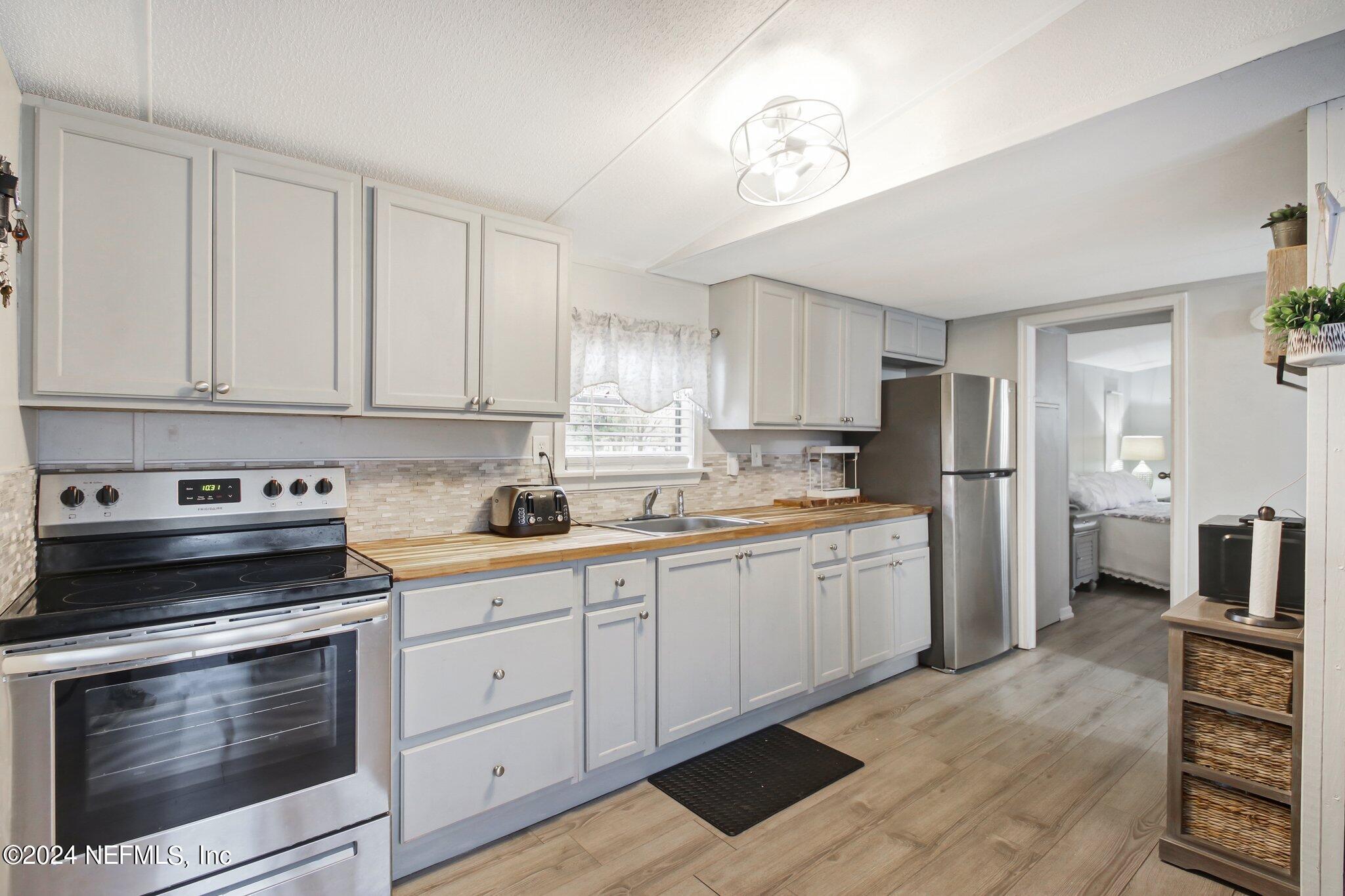 3996 Pinto Road Middleburg, FL 32068 - Photo 13 of 26 a kitchen with granite countertop white cabinets and stainless steel appliances