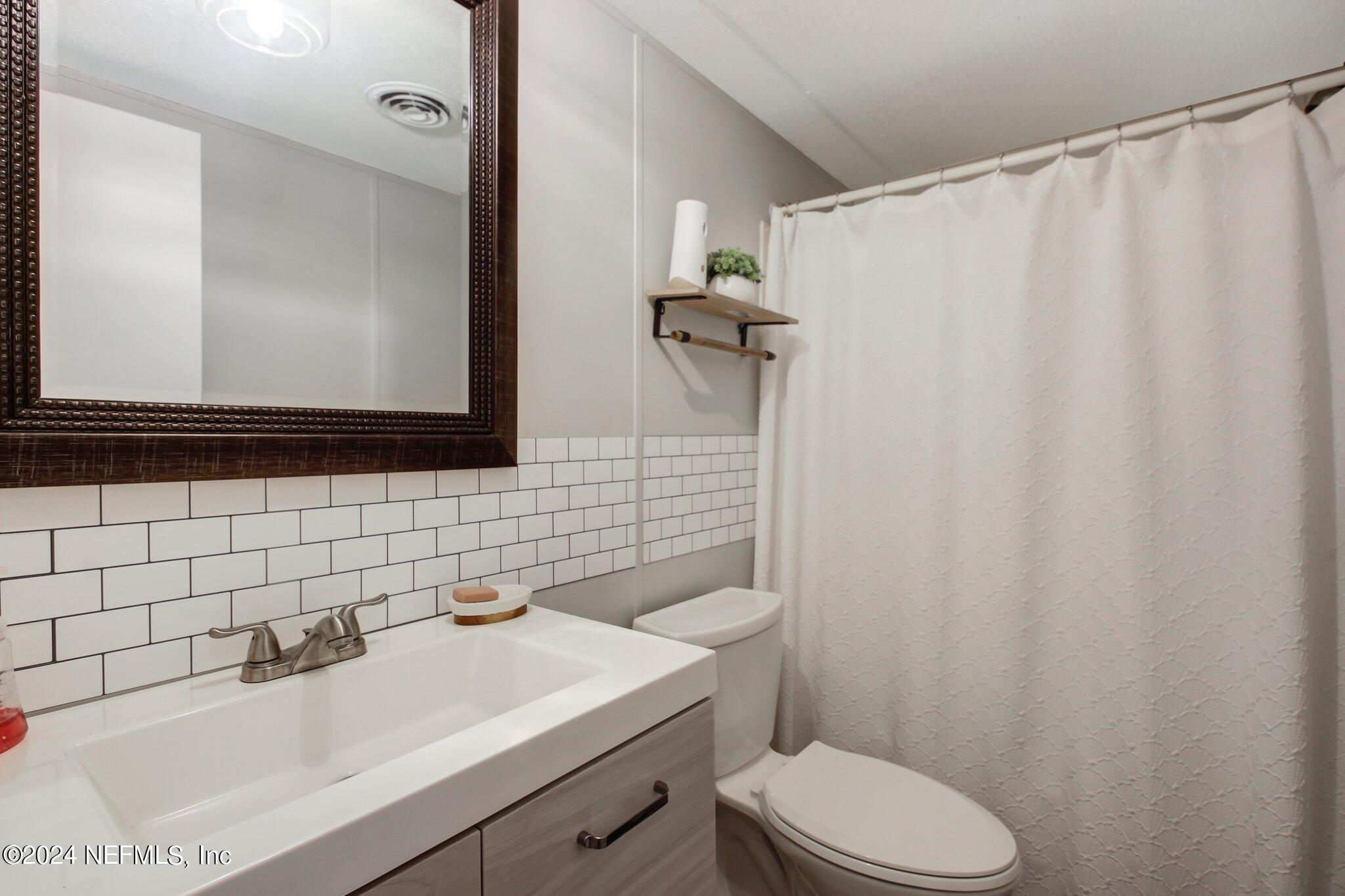 3996 Pinto Road Middleburg, FL 32068 - Photo 24 of 26 a bathroom with a sink a toilet and shower curtain