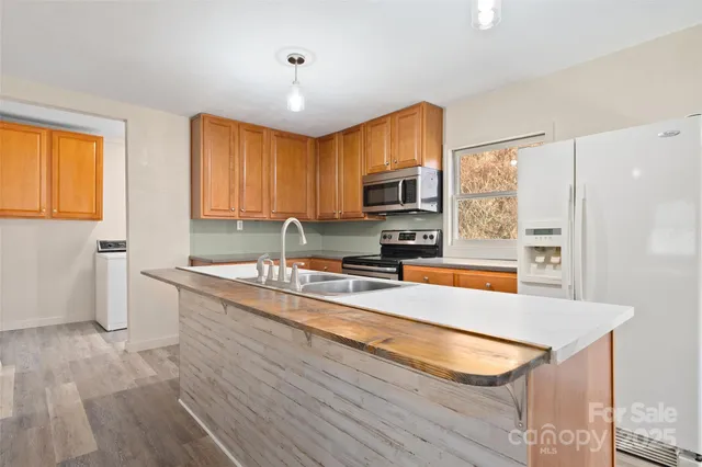 a kitchen with stainless steel appliances granite countertop a sink a stove and a wooden floors