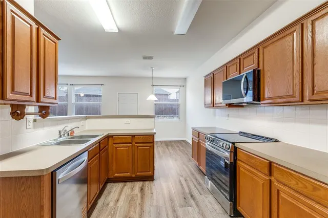 a kitchen with stainless steel appliances granite countertop wooden cabinets stove top oven and sink