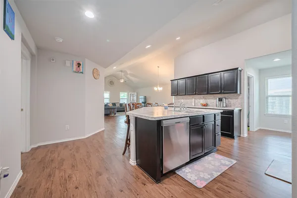 a large kitchen with stainless steel appliances kitchen island granite countertop a large counter top and wooden floors
