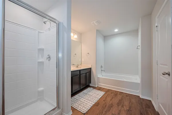 a bathroom with a tub sink vanity granite and shower