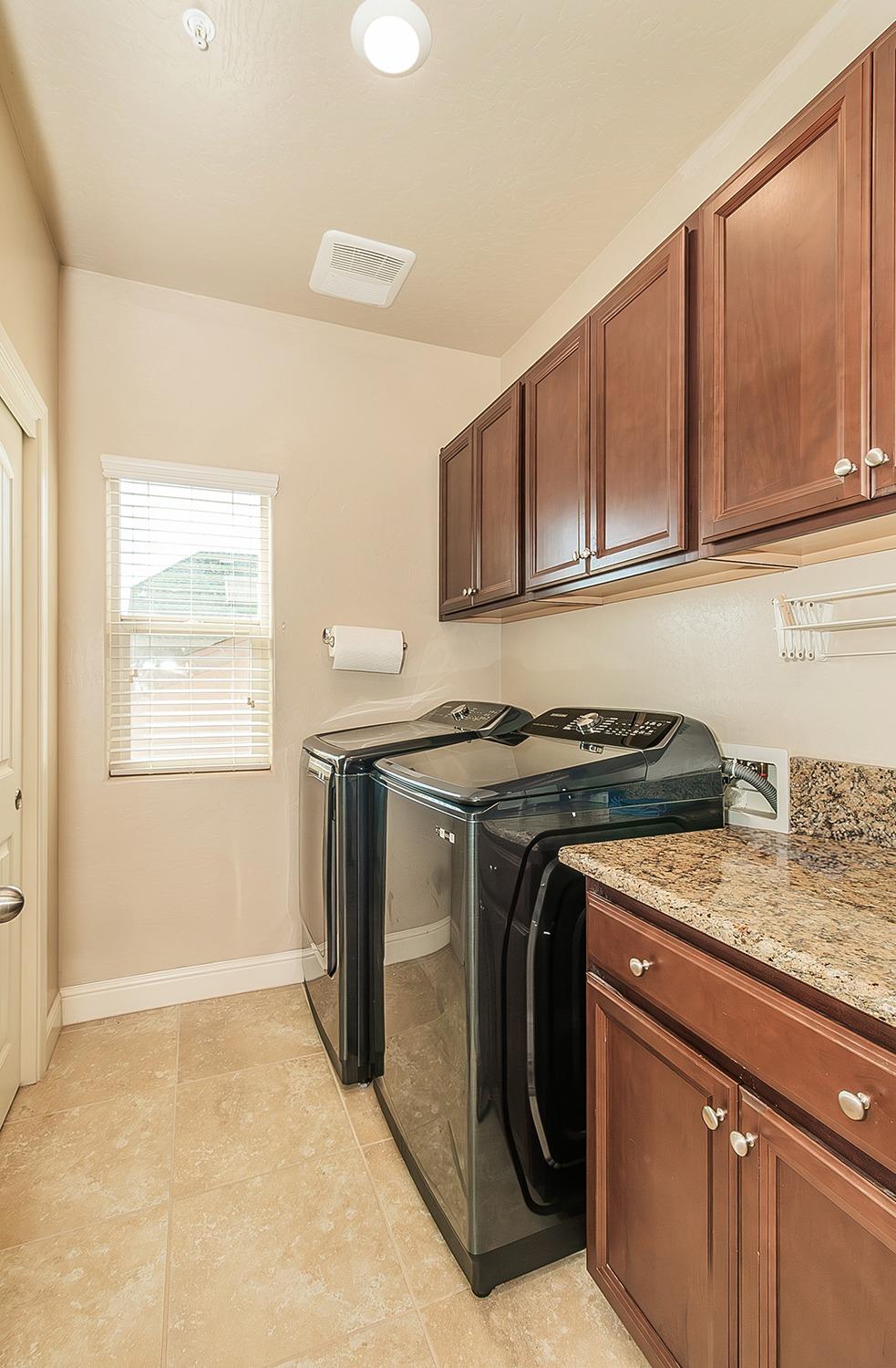 2043 North Soledad Avenue Clovis, CA 93619 - Photo 25 of 33 a utility room with granite countertop a sink a washer and dryer with wooden cabinets